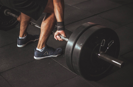 Athlete in the midst of an intense weightlifting session is contemplating the advantages of collagen protein vs whey protein
