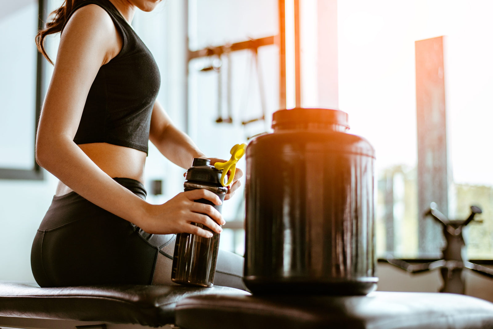 Female athlete holding a bottle of easy to digest protein shake at a gym