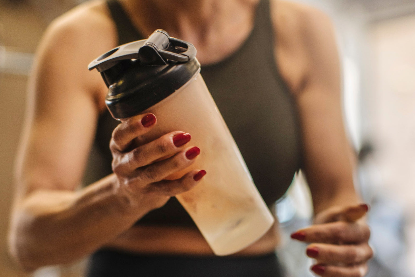 Sportswoman mixing whey protein with water in a shaker while wondering, "Is whey protein good for women?"