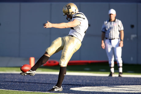 Football player practicing on the field while being supervised by his coach as part of his football conditioning program