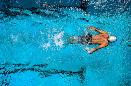 Bird’s eye view of a male triathlete swimming competitively in a pool as a result of having proper nutrition for runners and triathletes