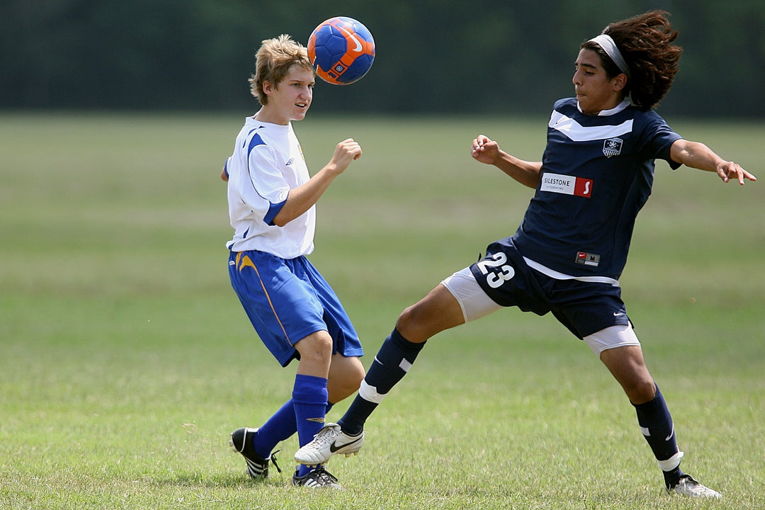 Two teenage athletes are wondering, "Can kids have protein powder?" during soccer practice