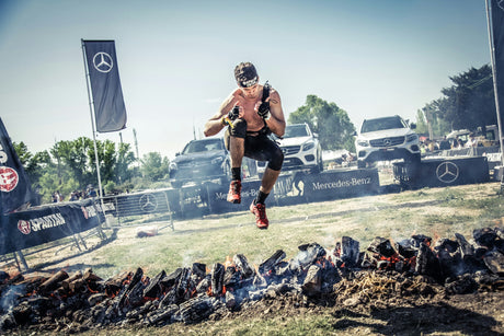 OCR athlete who has achieved his protein goals for weight loss is jumping over flaming coals 