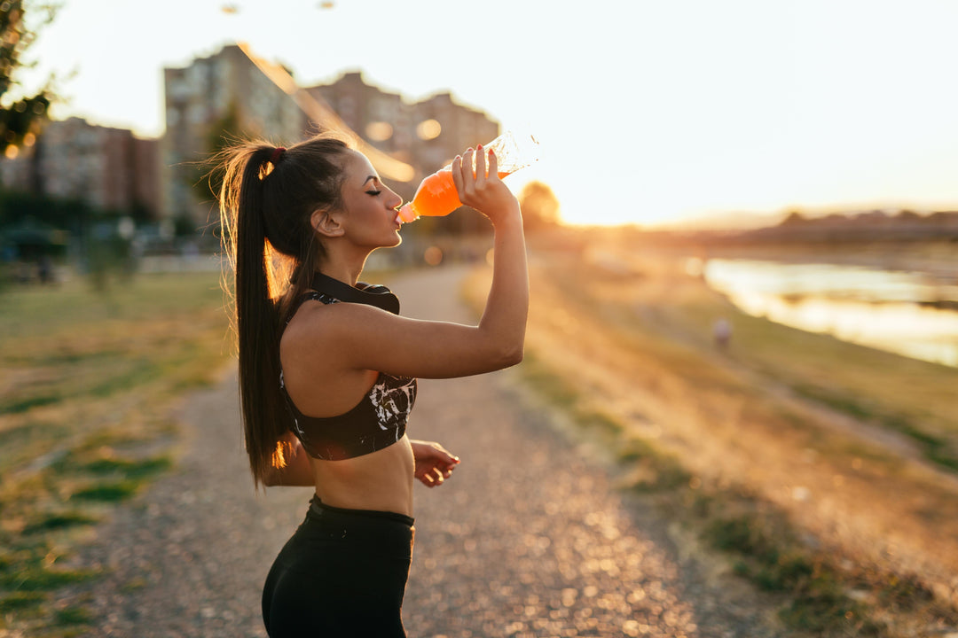Athletic woman unfamiliar with sports drink nutrition facts is drinking an electrolyte drink while outdoors