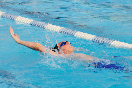 Competitive teen swimmer who regularly intakes protein shakes for kids is racing in a pool