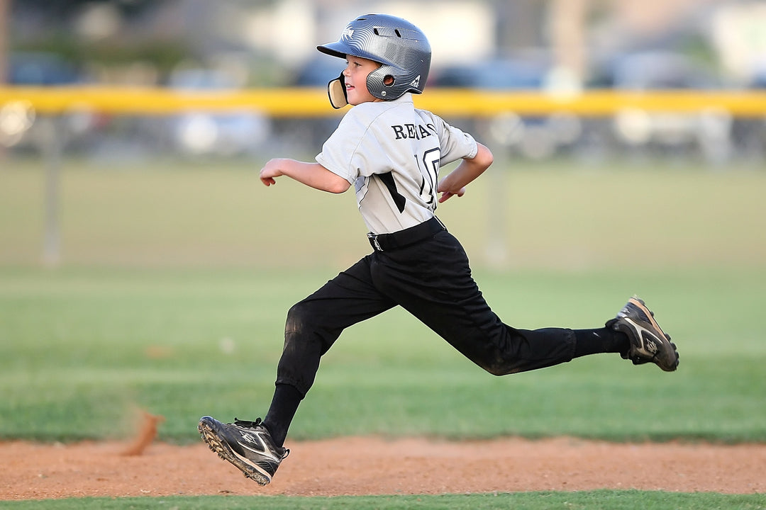 Young baseball player energized by the best protein powder for kids is running to the base
